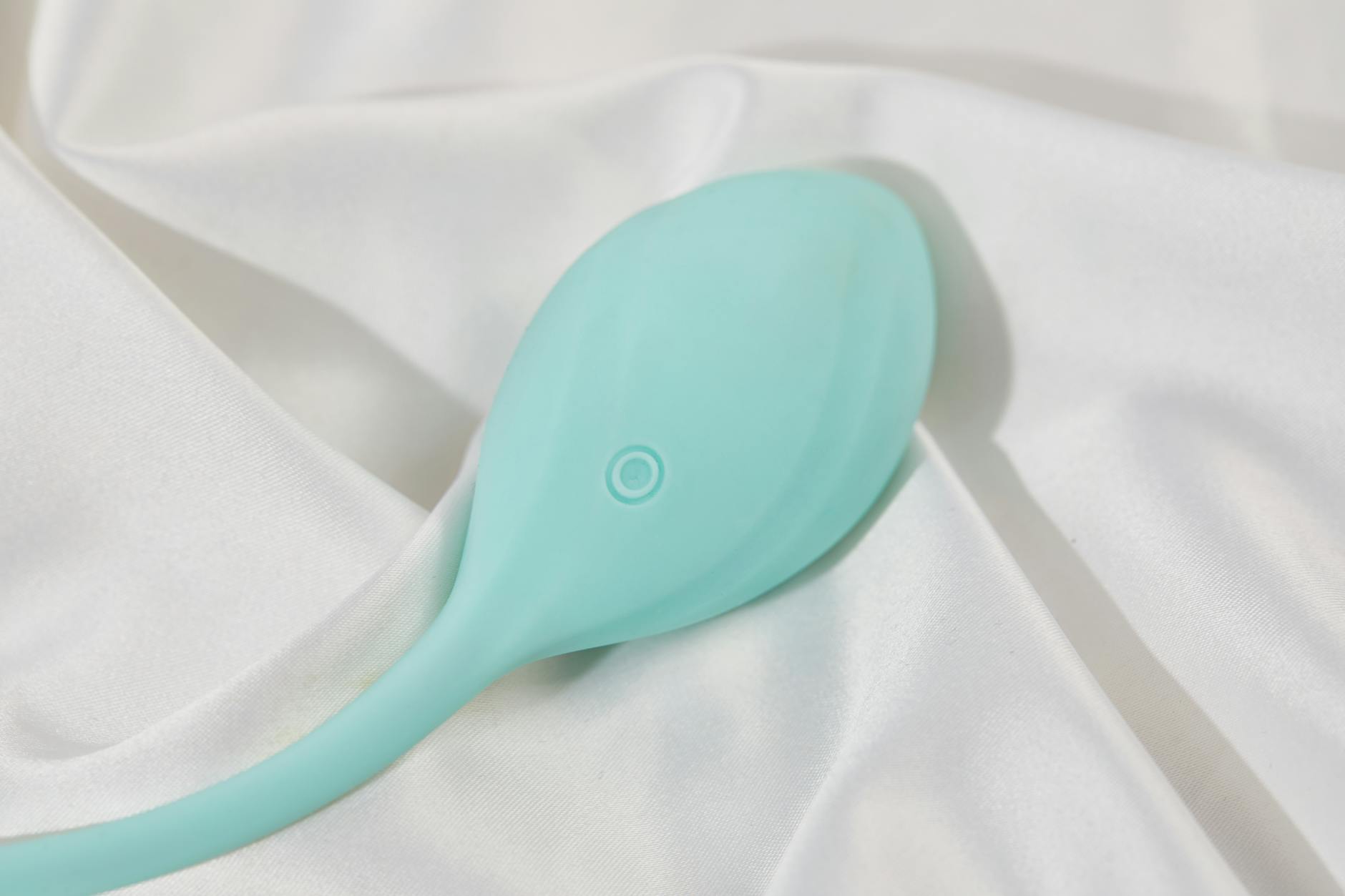 A teal lemon vibrator on smooth white silk, representing comfort and pleasure
