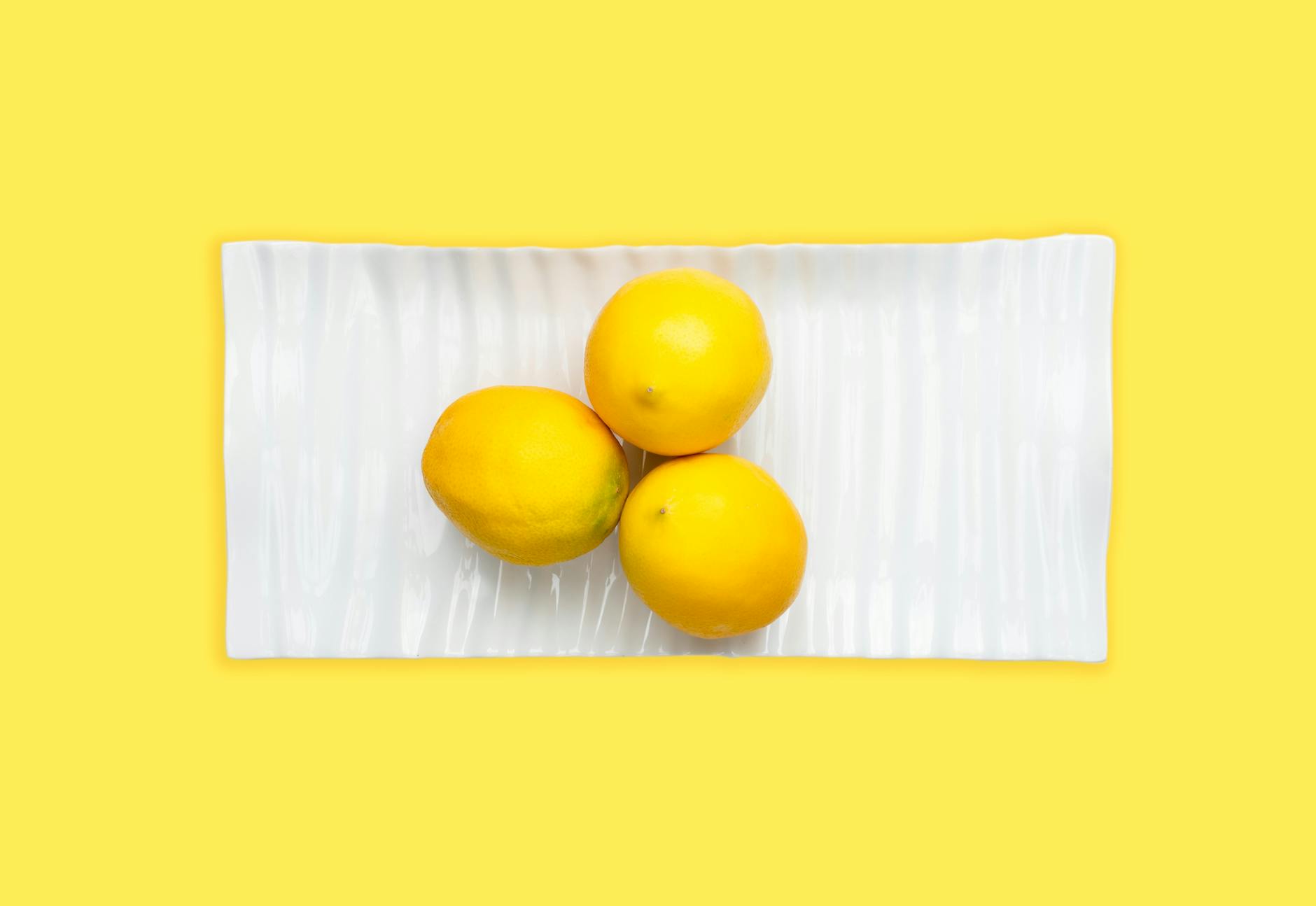 Two fresh lemons held gently in cupped hands on a warm surface, symbolizing care and gentleness with yourself