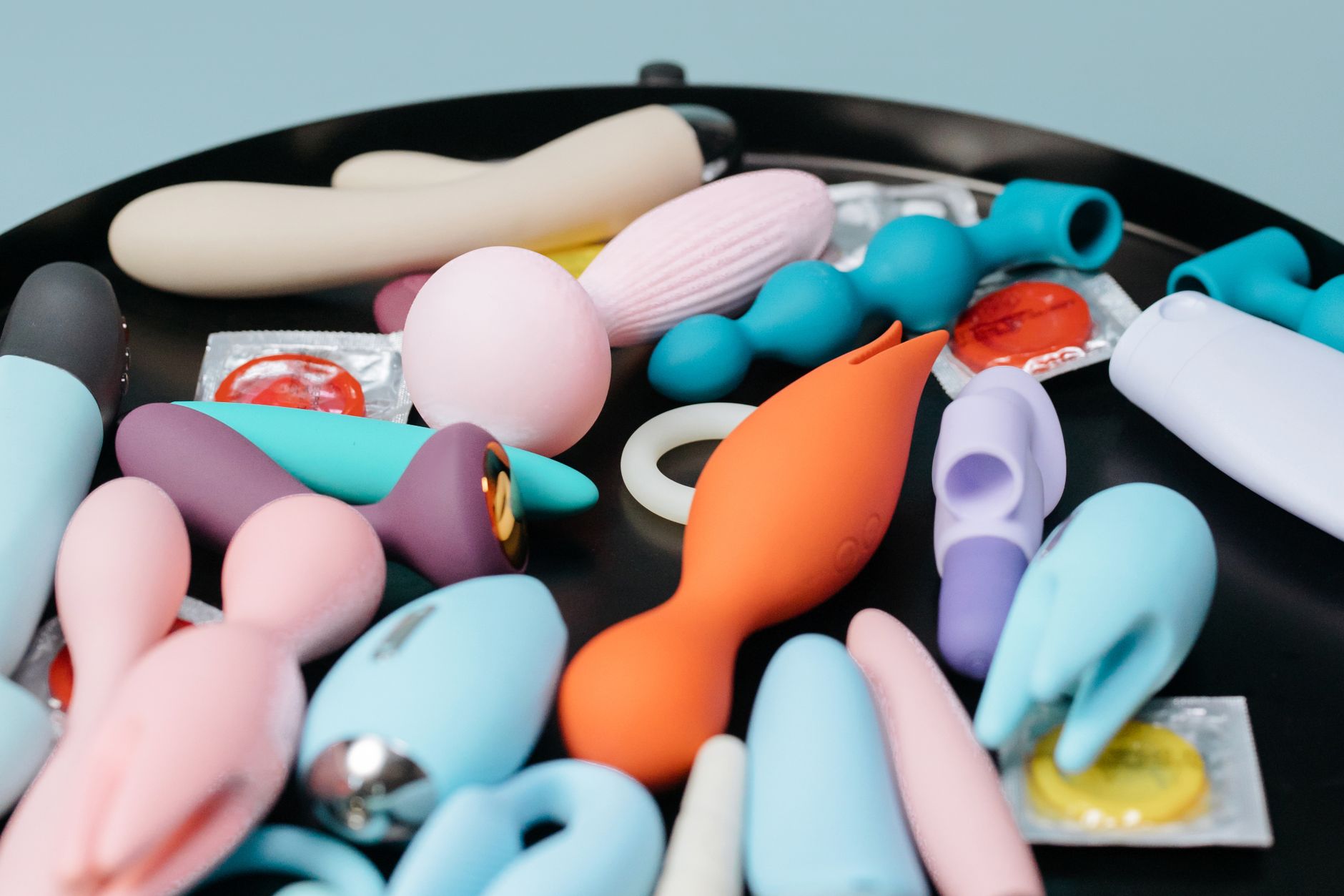 A collection of colorful adult toys on a black tray showing various vibrator designs and shapes