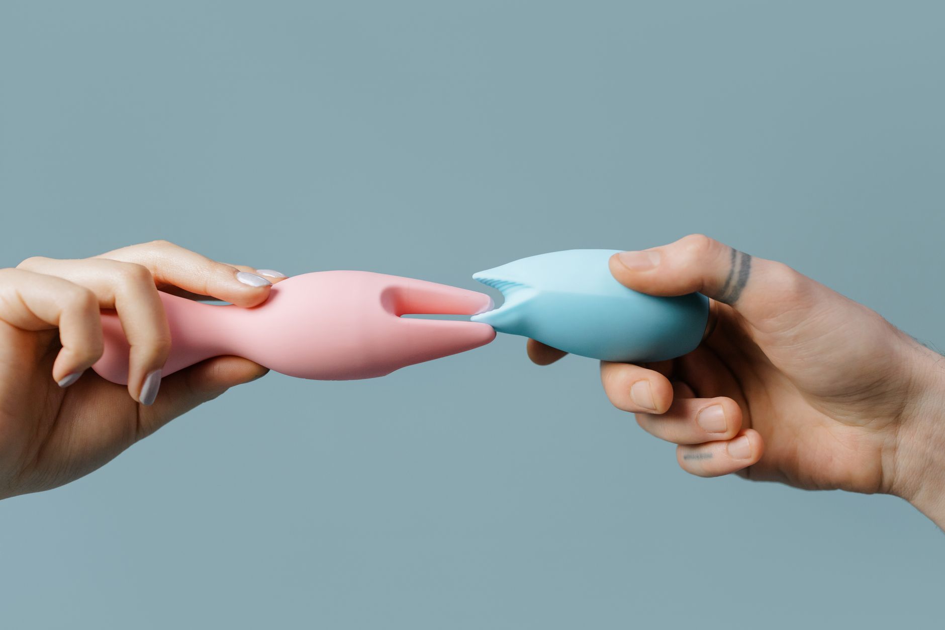 Gros plan des mains tenant un vibromasseur bleu contre un fond violet