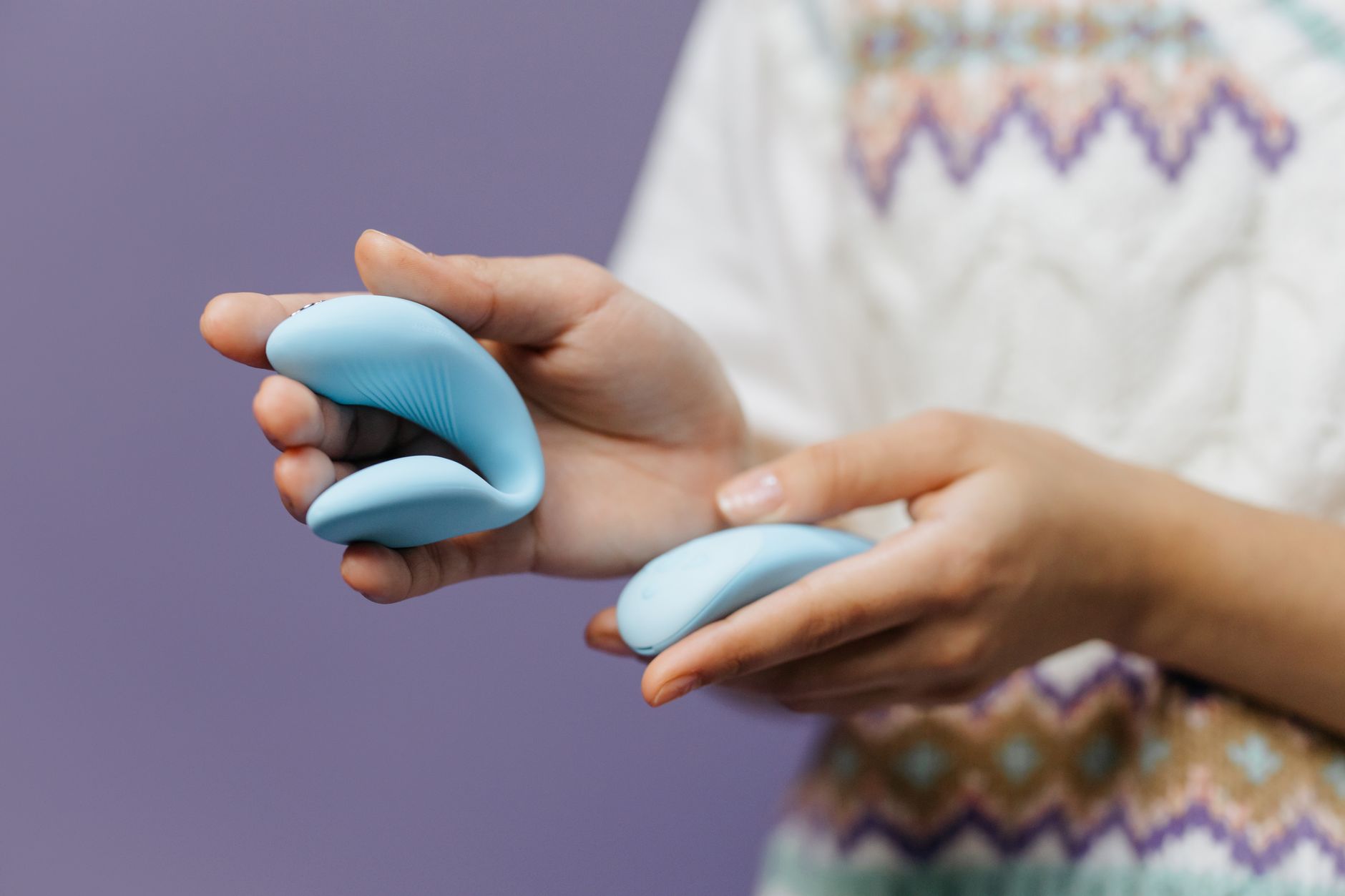 A hand holding a sleek blue vibrator, representing personal pleasure and self-care during relationship transitions.