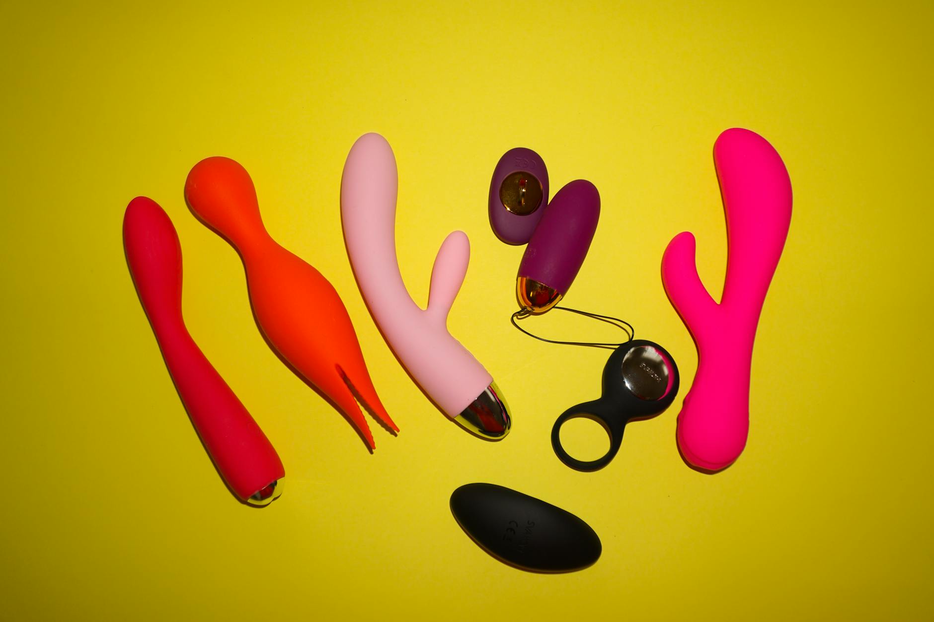 Colorful vibrators arranged on a bright yellow background, symbolizing pleasure and choice in intimate moments
