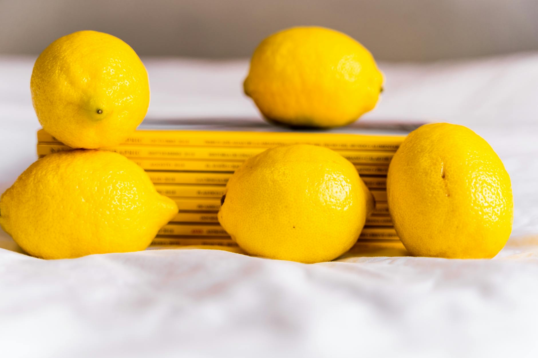 Fresh lemons with stacked books on white cloth, symbolizing mindful timing and preparation